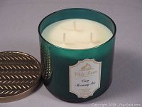 Close-up of the large scented candle showing three wicks and the label on the container.