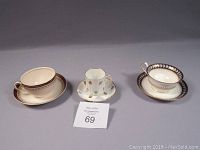 Three different cups and saucers from Limoges, Alfred Meakin, and Wedgwood displayed side by side.