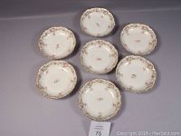Seven porcelain soup or cereal bowls arranged to show floral decorative pattern around scalloped rim with gold trim