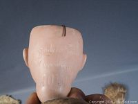 Close-up of the back of the antique bisque doll head showing the embossed mark 'Armand Marseille 402M'