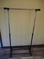 Assembled adjustable garment rack showing metal construction with black base and adjustable horizontal bar.