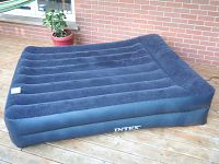 Full view of the inflated blue Intex queen air mattress on wooden deck floor with soft velvety top.