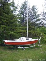 Port side view of red hull and white deck on trailer