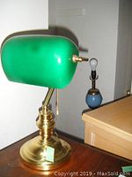 Blue spherical table lamp with brass accents and exposed bulb, smaller lamp in background.