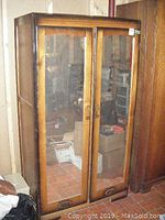 Front view of vintage wooden armoire with two mirrored doors showing reflective glass and wood frame condition.
