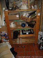 Front view of wooded pine shelf showing various cardboard boxes, frames and small decorative objects on shelves.