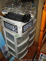 Photo of two rolling plastic storage containers stacked with a box on top containing additional items and black plastic hangers on the surface.