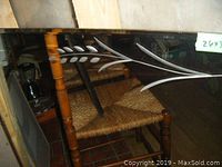Close-up photo of corner of rectangular mirror showing painted white leaf design on the glass edge and chair reflection.