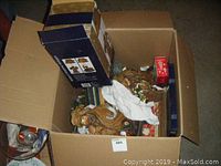 Open top view of box showing assorted decorations including wooden figurines and holiday items
