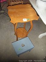 Wooden plant stand with scalloped edges and a small blue step stool with a heart cutout on top, both showing minor wear.