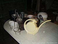 Overview photo showing all items on a white surface including watering cans, ceramic and plastic plant pots, and a miniature gardening set