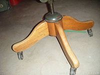 Close-up view of the wooden base with caster wheels and height adjustment screw