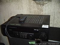 Front and top view of the Kenwood VR-407 with remote control on top, showing vented top and front control panel.