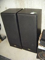 Pair of black Vivid Reference floor-standing speakers with wood finish and black fabric grilles in place, positioned side by side.