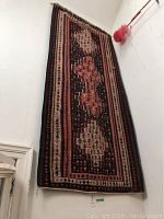 Full view of the Kilim rug hanging vertically on the wall showing its length and pattern.