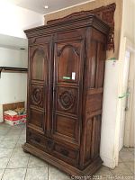 Front three-quarter view showing carved double doors and lower drawers
