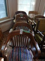Front and top view of six wooden chairs positioned close together showing armrests and slatted backs, one with colorful woven seat cushion.