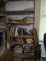 Bookshelves with mixed books ranging in size and color, some stacked horizontally and others vertically.