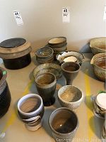 Multiple handmade pottery bowls including footed and small bowls in brown, beige, and black tones, shown assembled on table.