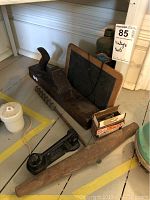 Vintage tools displayed including large wooden hand plane, small chalkboard, metal nutcracker, wooden drill arm, jar, and box of screws.