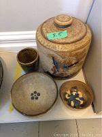 Four-piece pottery set including lidded jug, cup, and two bowls on display.