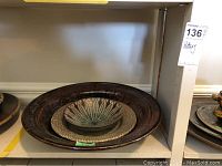 Three nested decorative pottery bowls arranged on a shelf with intricate glaze and patterns visible
