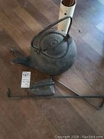 Photo showing cast iron kettle, iron flat iron, and fire poker on floor