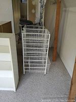 Three white metal storage racks with wire mesh drawers grouped together in a room.