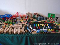 Full overview of the assembled wooden train track with trains, buildings, bridge, tunnels, and accessories on a green cloth surface
