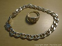 Sterling silver chain bracelet and ring on a wooden surface, both stamped .925