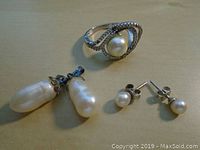 Overall view of ring and two pairs of freshwater pearl earrings on beige surface