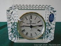 Front view of the clear crystal clock showing the faceted edges and the Roman numeral clock face with the Royal Doulton logo and quartz label.