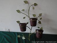 Full view of metal hanging planter showing three dark brown pottery-style pots attached to a leafy metal vine frame.