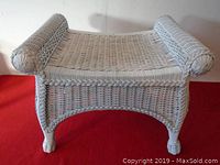 Front view of white painted wicker stool showing woven seat and rounded ends.
