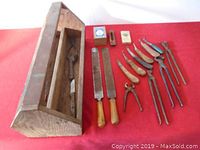 Photo showing wooden tool box, rasps, hoof knives, pincers, and tongs arranged side by side