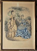 Framed engraving plate showing two 1870s French fashion women in an outdoor setting with potted plants, under glass with wood frame.