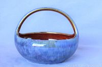 Front view of the porcelain lustre basket showing the blue-purple glaze and coppery lustre inside and on the handle