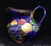 Front side showing hand-painted fruit on deep blue background with glossy glaze