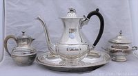 Front wide shot of the entire silver plate tea set including the teapot, creamer, sugar bowl, and tray on a neutral background.