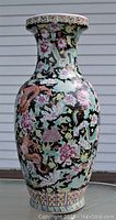 Front view of the large vintage Chinese porcelain vase showing the painted relief dragons and flowers on a black background with crackle glaze.