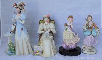 Front view of all four ceramic lady figurines showing detailed attire and poses