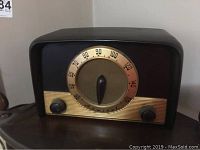 Front view of vintage tube radio with tuning dial and control knobs on wooden surface.