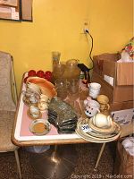 Assortment of luncheon plates, mugs, cups, glass serving dishes on a table including various sizes and patterns