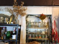 Shelving holding various glassware items including parfait glasses, glass server, and decorative vases. Shelves dusty and items appear heavily used.
