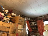 View of top shelves with various glassware items including white milk glass vases, red glass bowl, and boxed items below.
