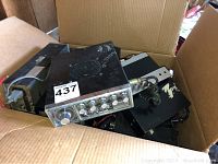 Photo of multiple vintage CB radios in a cardboard box showing the top radio with metal casing and speaker grille.