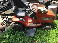 Side profile shot of orange Scotts riding mower showing seat, steering wheel, cutting deck and tires.