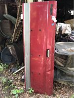 Full view of the red tailgate leaning vertically showing signs of rust and surface damage.