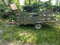 Side view of flatbed trailer showing wooden slatted sides and metal frame with rust