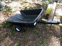 Black plastic utility trailer LD-8 model sitting on ground with some outdoor debris around, showing overall shape and tow arm.
